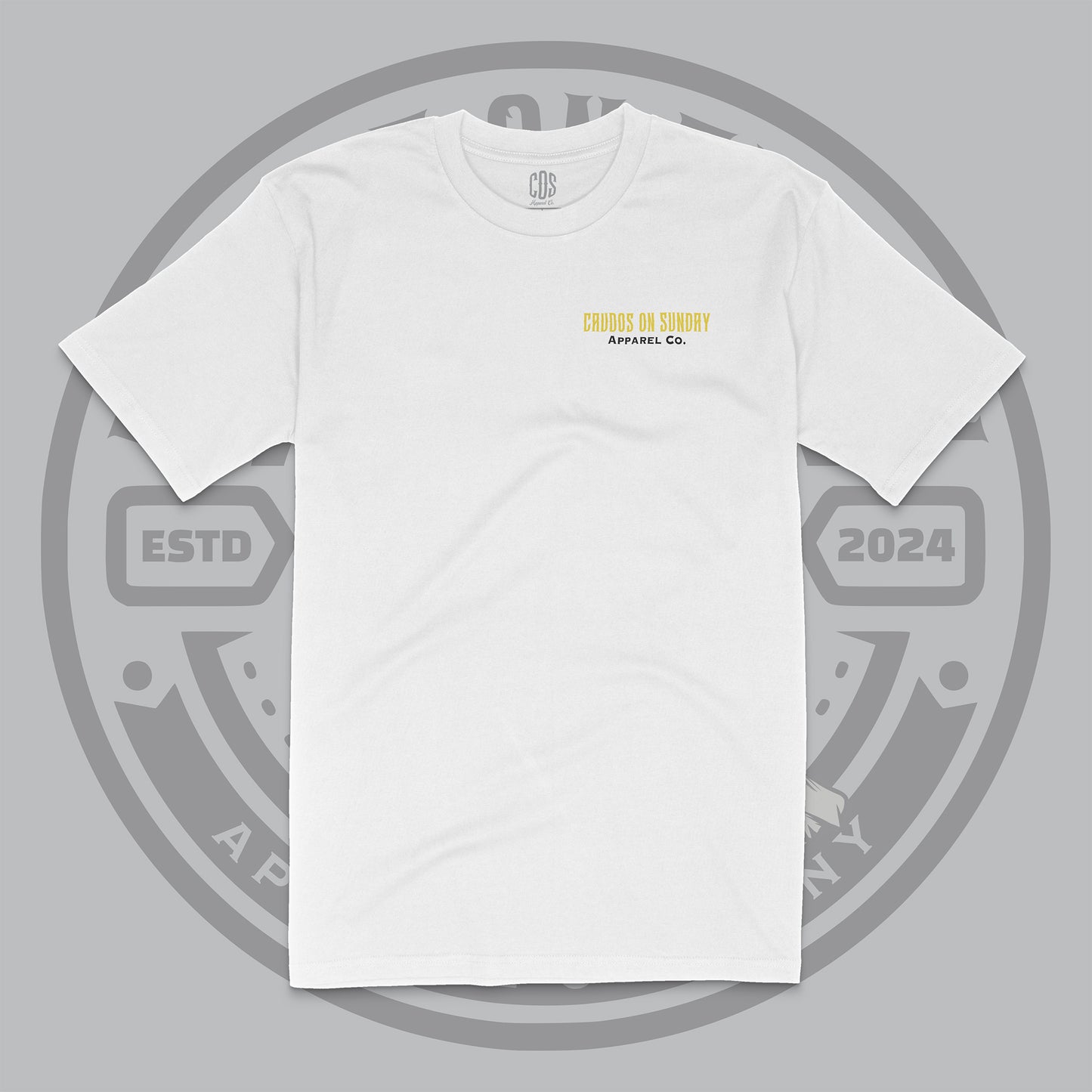 White t-shirt with small “Crudos On Sunday Apparel Co.” logo printed on the left chest in yellow and black